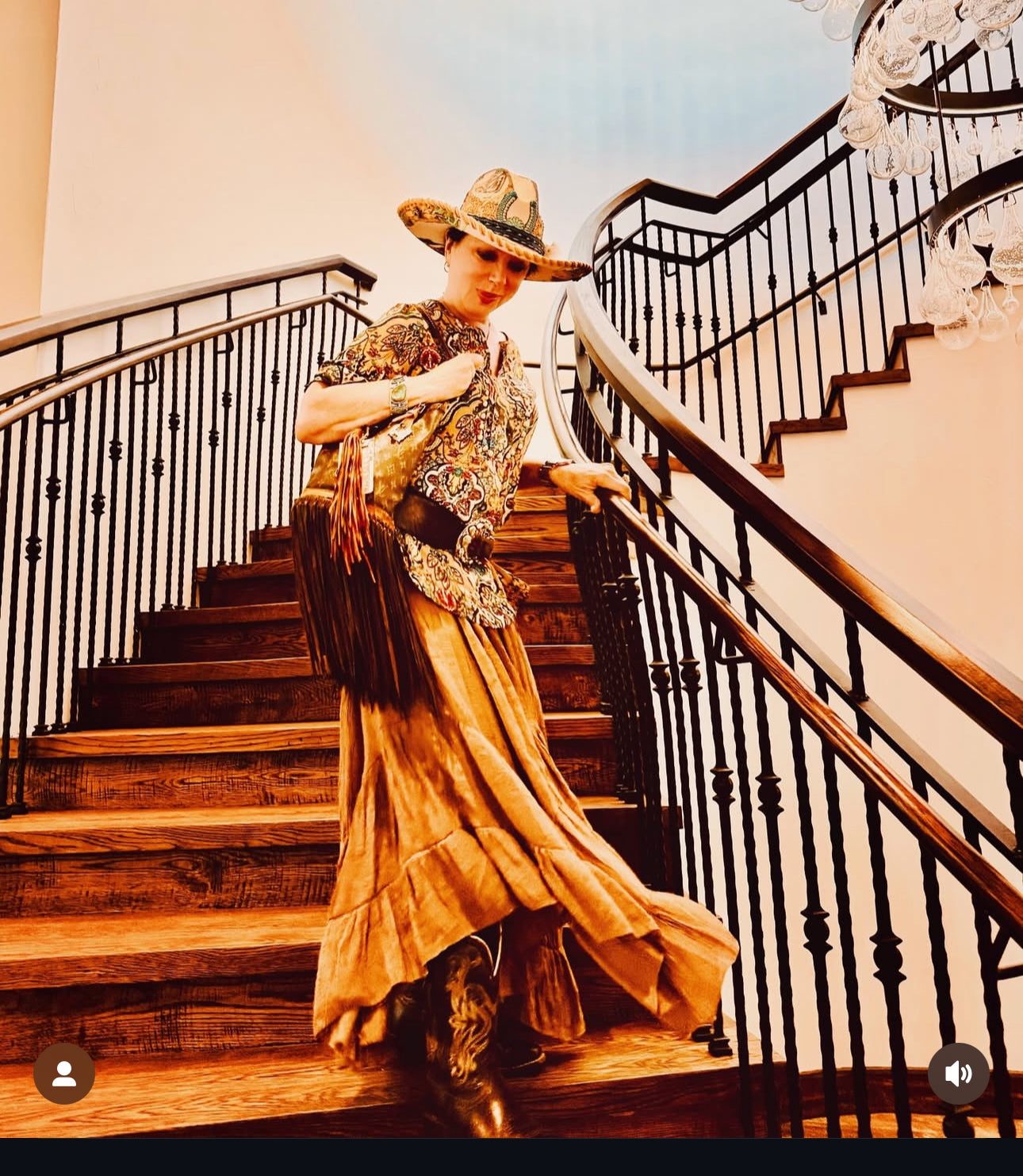 Woman in a long, elegant dress and hat standing on a staircase